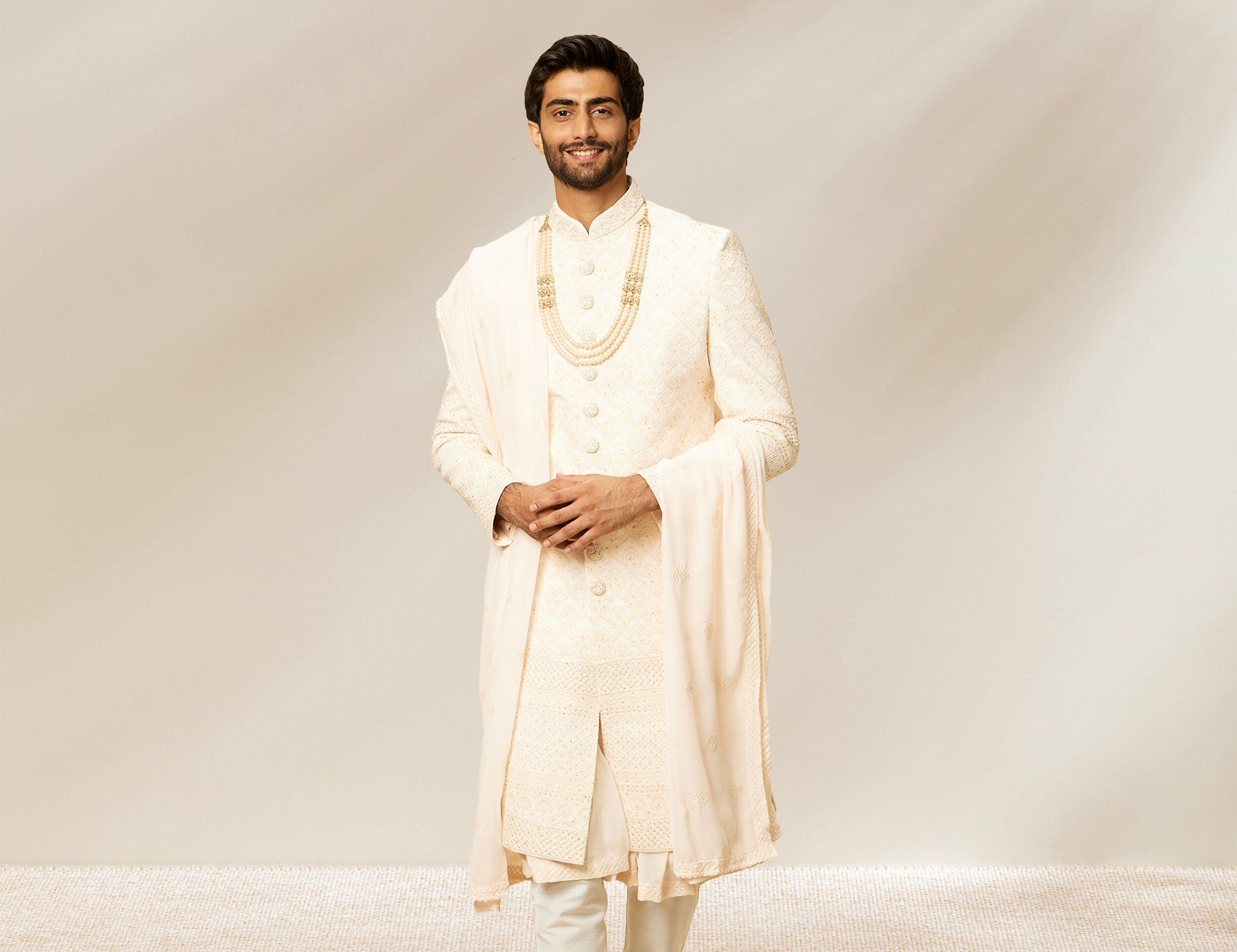 A man in elegant white sherwani with white dupatta